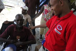 Olgens Toussaint, a monitor for the disabilities program, visits with one of the people Service Chretien of d'Haiti is helping